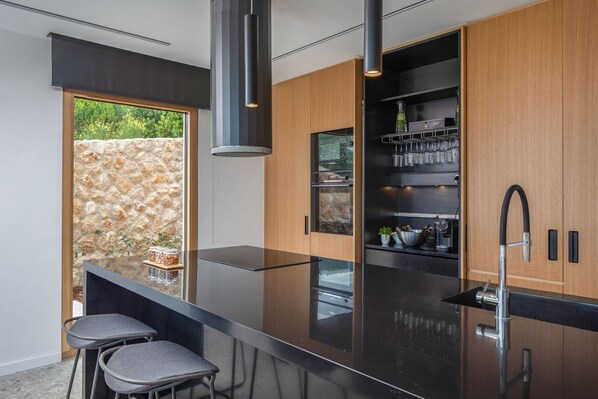A modern kitchen with a central island, bar stools, and a built-in wine rack.