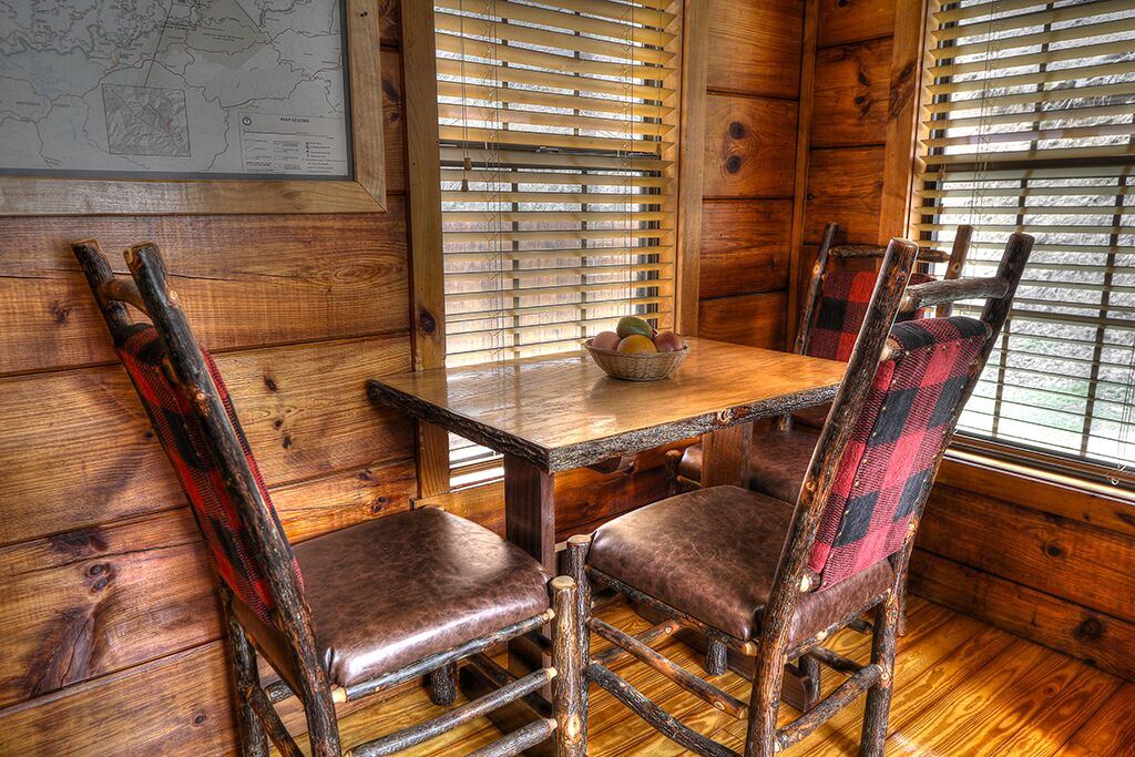 A wooden interior with a table and chairs, a map on the wall, and a window with blinds.