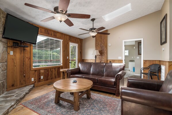 A living room with a brown leather sofa, a wooden coffee table, and a ceiling fan.