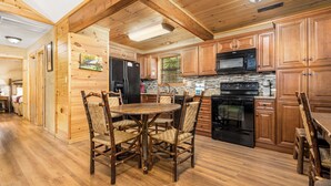 Une cuisine de style rustique, avec des éléments en bois, comprenant une table et des chaises, un réfrigérateur, une cuisinière, un four à micro-ondes et des placards en bois.