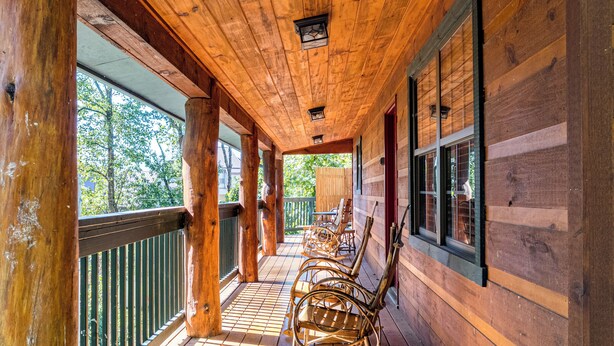 Une véranda en bois avec une balustrade, un plancher en bois et des fauteuils à bascule.