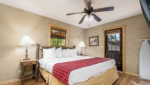 Une chambre à coucher comprenant un lit, deux tables de chevet avec des lampes, un ventilateur de plafond, une fenêtre avec vue et une porte.