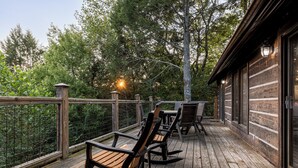 A wooden deck with outdoor furniture and a view of trees.