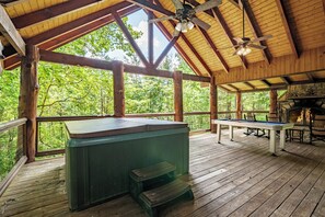 Eine Holzterrasse mit Whirlpool, Billardtisch und Sitzgelegenheit, umgeben von Bäumen.