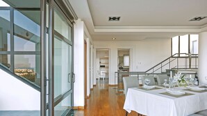 Een moderne eetruimte met een lange tafel gedekt voor een maaltijd, een trap en uitzicht op de omgeving.