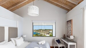 Un dormitorio con cama, escritorio, silla, ventana con vistas y lámpara colgante.
