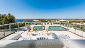 Eine Dachterrasse mit Pool, Sitzgelegenheiten und Blick auf die Küstenlinie.