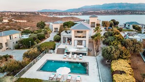 Un resort moderno con piscina, sillones de descanso y vista al mar.