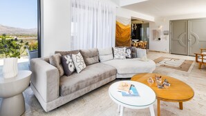 Ein modernes Wohnzimmer mit einer Couch, einem Couchtisch und Blick ins Freie.