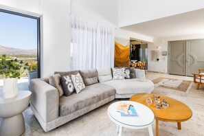 A modern living room with a sofa, a coffee table, and a view of the outdoors. - Sea View Villas - Four Bedroom Villa, Sleeps 8 (Chania)