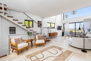 A spacious living area with a staircase, a sofa set, a coffee table, and a view of the outdoors. - Sea View Villas - Four Bedroom Villa, Sleeps 8 (Chania)