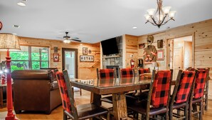 A wooden interior with a dining table, chairs, and a fireplace.