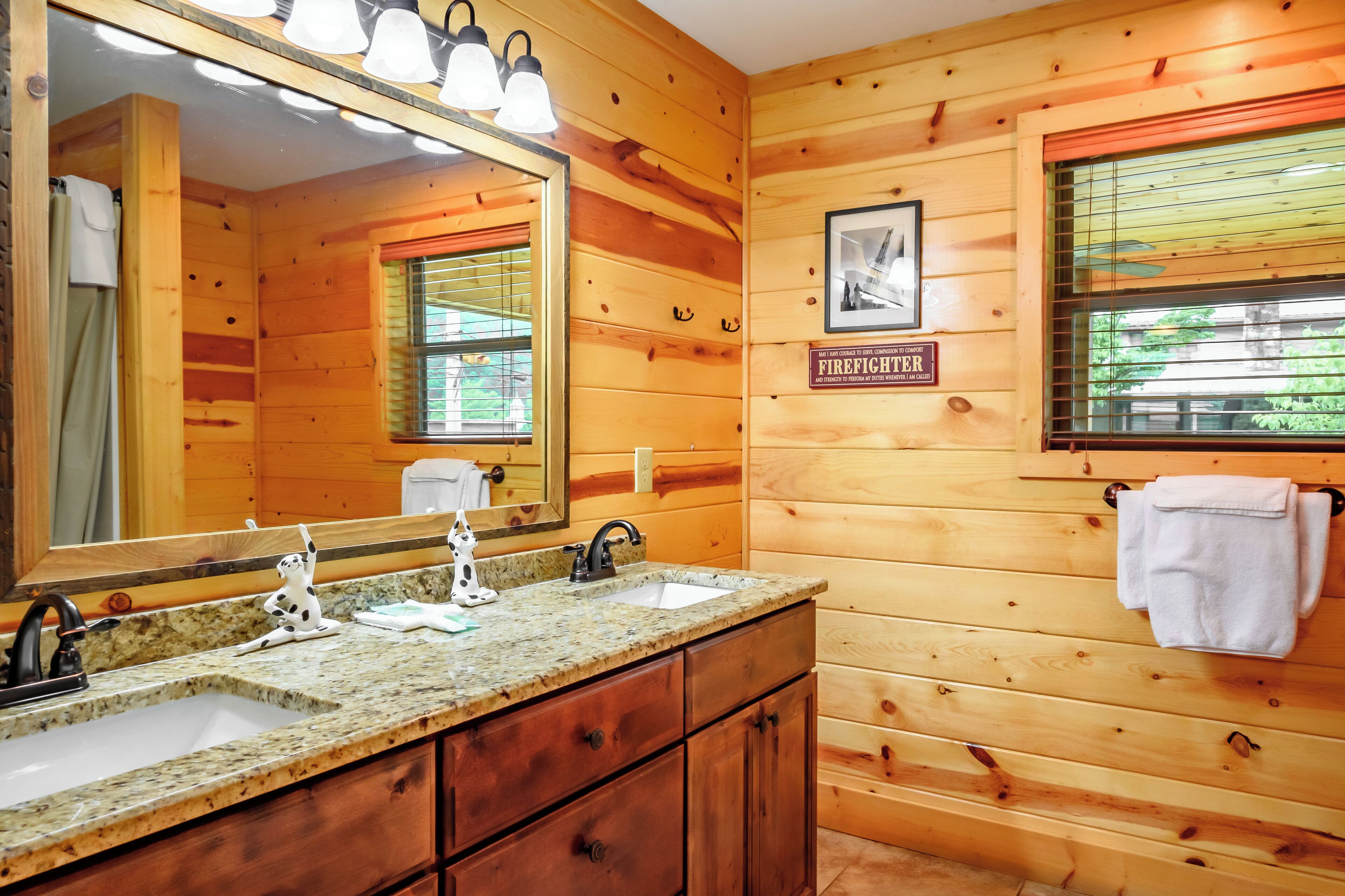Un baño de cabaña de madera con dos lavamanos, un espejo y un perchero para toallas.