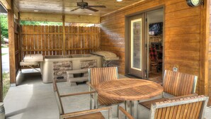 An outdoor patio with a wooden table and chairs, a barbecue grill, and a ceiling fan.