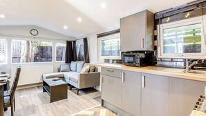 A modern kitchen with a built-in microwave, a dining area with a table and chairs, and a sofa. - 2 bedroom accommodation in Abbotskerswell, nr Newton Abbot (Abbotskerswell, nr Newton Abbot)
