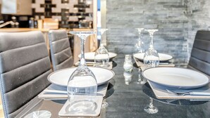 A dining table set with plates, cutlery, and wine glasses, surrounded by upholstered chairs. - 2 bedroom accommodation in Abbotskerswell, nr Newton Abbot (Abbotskerswell, nr Newton Abbot)