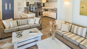 A modern living room with a sofa, coffee table, and a dining area with a kitchen in the background. - Villa Aliki - Five Bedroom Villa, Sleeps 10 (Kassiopi)