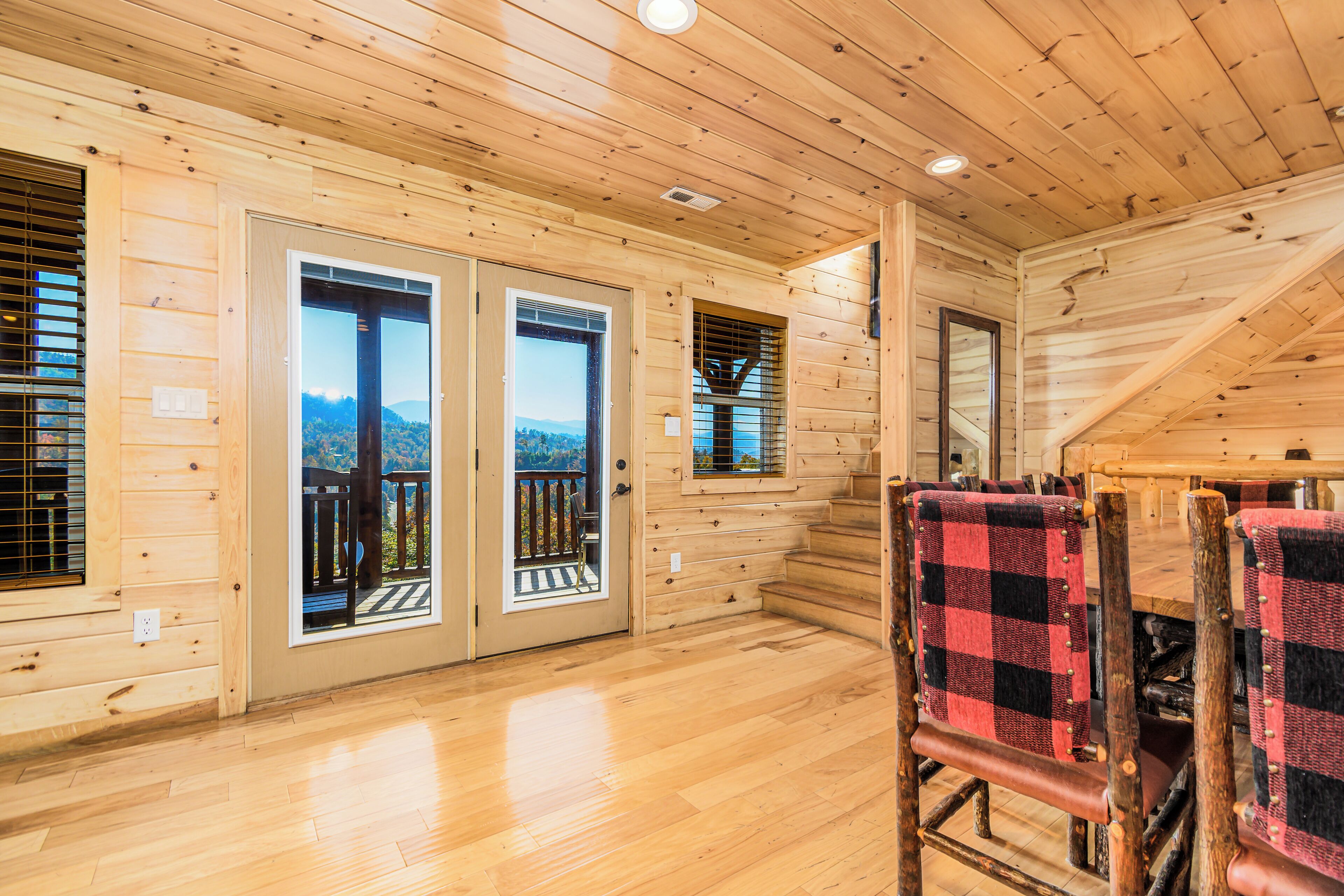 L’intérieur d’un chalet en bois comprend un coin repas, deux portes donnant sur un balcon et une vue sur les montagnes.