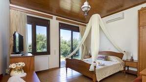 A bedroom with a wooden bed, a television, a desk, and a window with curtains.