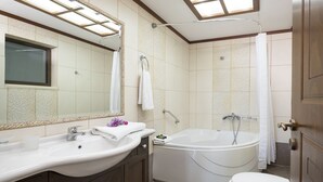 A modern bathroom with a large bathtub, a separate toilet, and a vanity with a mirror.