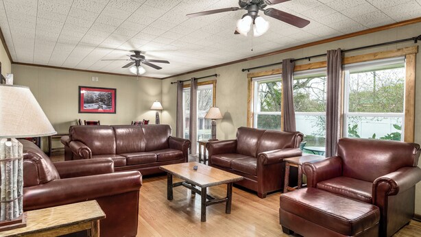 Ein geräumiges Wohnzimmer mit Ledersofas, einem Holztisch und Deckenventilatoren.