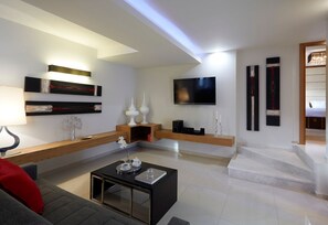 A modern living room with a flat-screen TV, a coffee table, and a sofa.