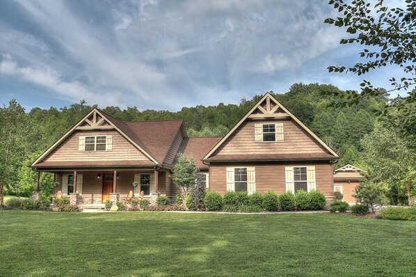 A two-story house with a symmetrical design, featuring a front porch, a covered entryway, and a landscaped front yard.