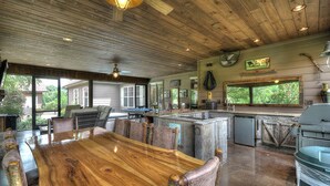 Una cocina rústica con una gran mesa de madera, electrodomésticos empotrados y amplias ventanas con vistas al exterior.