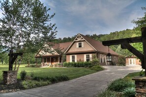 A two-story house with a prominent front porch, a stone entryway, and a well-maintained lawn.