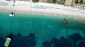 Vista aérea de una playa con aguas turquesas cristalinas, una orilla arenosa y algunas embarcaciones.