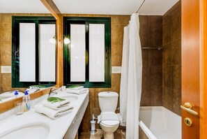 Une salle de bain avec deux lavabos, des toilettes, une baignoire et un rideau de douche.