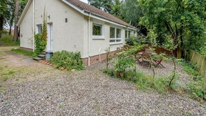A single-story house with a sloped roof, a small front porch, and a gravel driveway. - Burnside West Cottage- UK39596 (St Andrews)