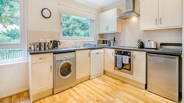 A modern kitchen with a washing machine, oven, microwave, and dishwasher. - Burnside West Cottage- UK39596 (St Andrews)