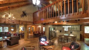A spacious lodge with a high ceiling, wooden beams, a dining area, and a kitchen.
