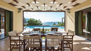 A dining area with a view of a pool and the sea.