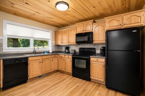 A kitchen with wooden cabinets, a black refrigerator, a microwave, a stove, and a dishwasher.