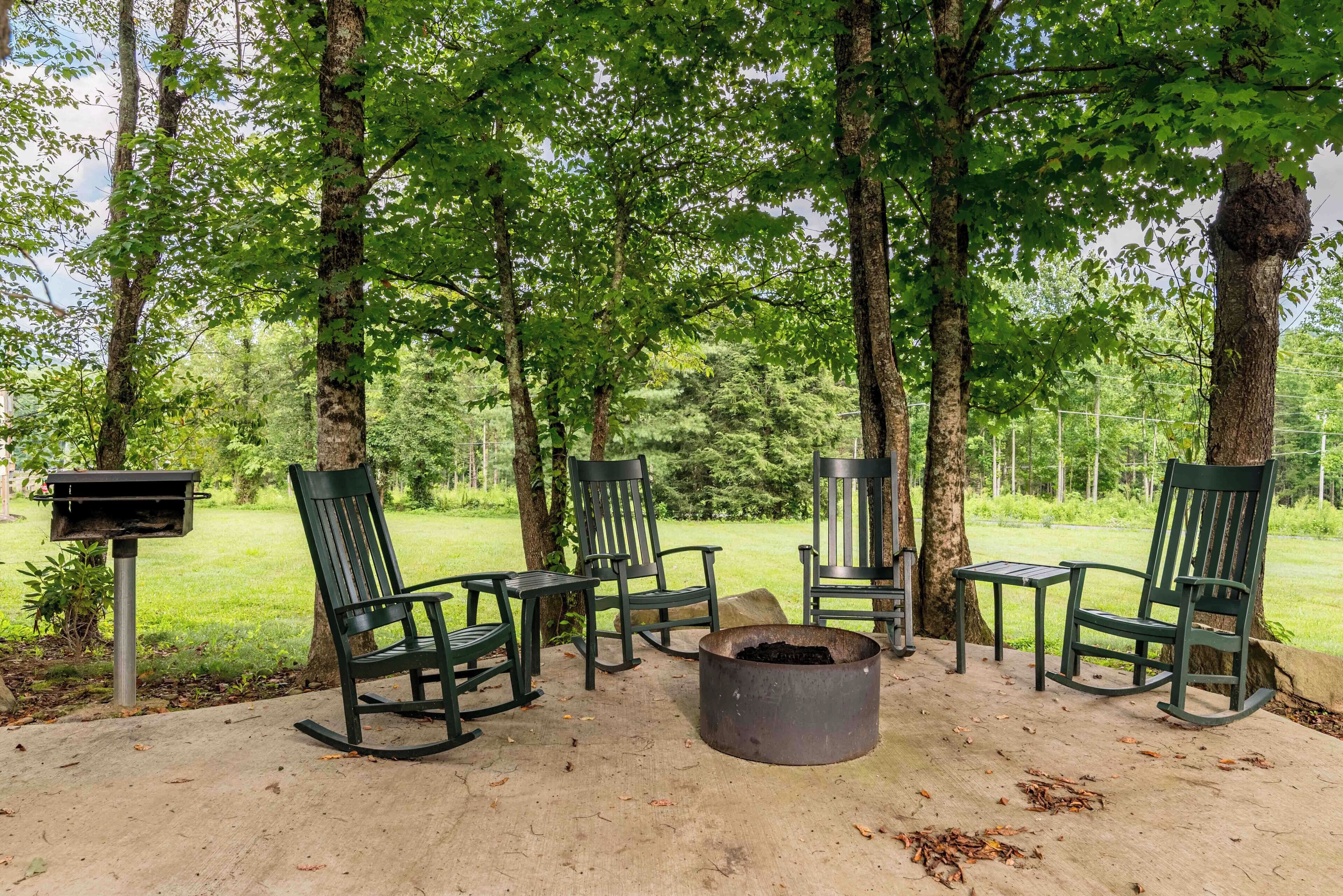 A covered outdoor seating area with four rocking chairs and a fire pit.