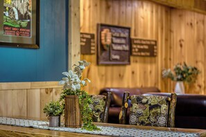 A wooden interior with a table, chairs, and a wall with signs. - Poppy’s Outpost • Hot Tub • Fire Pit • Family Fun (Cosby)