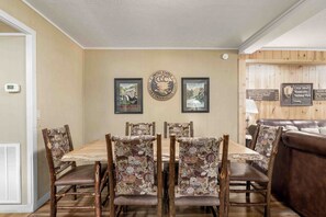 A dining area with a wooden table and chairs, framed posters on the wall, and a sign for Great Smoky Mountains National Park.