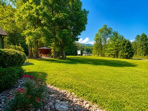 A well-maintained lawn with a gazebo, a stone pathway, and a mountain in the background.