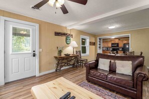 A living room with a brown leather couch, wooden coffee table, and a dining area with a table and chairs.