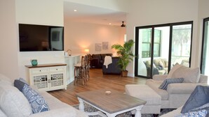 Una sala de estar con televisor, sofá, mesa de centro y un comedor con sillas y mesa.