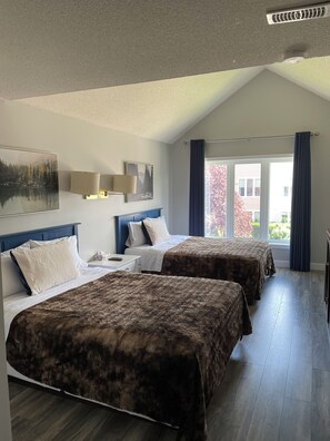 A hotel room with two beds, a large window with curtains, a ceiling fan, and a painting on the wall. - Spacious Resort Studio in Collingwood - 9 Min from Blue Mountain! (Collingwood)