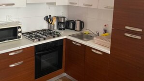 A kitchen with white cabinets, a microwave, stove, and a sink.