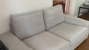 A grey sofa in a room with wooden flooring and a white wall.