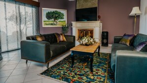 Una sala de estar moderna con chimenea, dos sofás, una mesa de centro y un ventanal con cortinas.