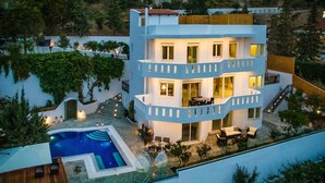 Un edificio moderno de varios pisos con piscina, mobiliario exterior y una escalera que lleva a un balcón.