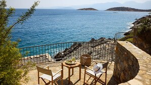 A stone deck with outdoor seating overlooking a coastal sea. - Thalassa Villas - Three-Bedroomed Private Pool Seafront (Agios Nikolaos)