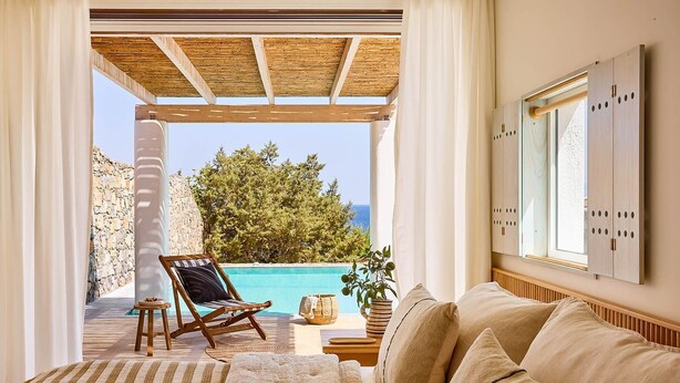 A cozy room with a view of a pool and the sea, featuring a wooden ceiling, a cushioned sofa, and a striped rug. - Thalassa Villas - Three-Bedroomed Private Pool Seafront (Agios Nikolaos)