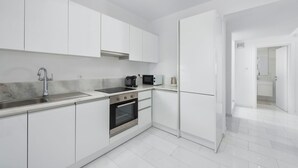 A modern kitchen with white cabinetry, a stainless steel sink, a built-in oven, and a microwave. - Villa Constantine - Six Bedroom Villa, Sleeps 15 (Kolympia)